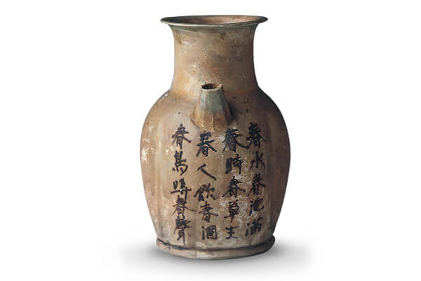 唐代．長沙窯枕+枕面呈橢圓形，下方有一獅子伏臥在方形板上，表面施青釉與褐彩為飾。（圖五）
