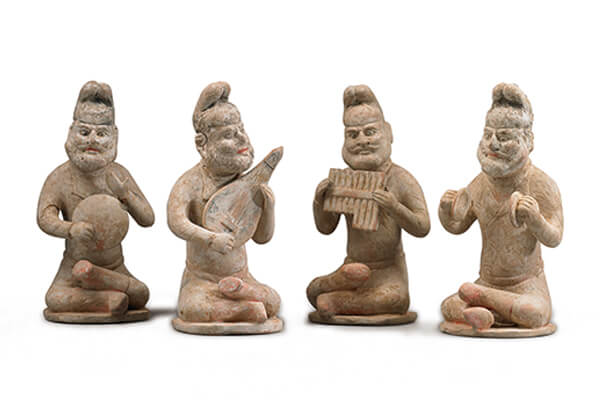 唐代．加彩胡人樂俑+四位胡人雙腿交疊盤坐在小圓氈上，手上拿著各式樂器，神情愉悅地演奏音樂。（圖三）