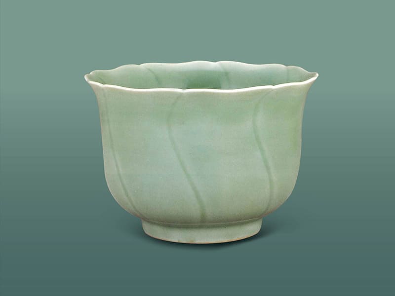 明宣德．仿龍泉青瓷葵口仰鐘式碗+模仿龍泉窯青釉，因?yàn)橛悦媪鲃?dòng)，口沿露白，陰刻S紋略顯深暗，色澤青翠素雅。（圖一）+圖片來源：《明代宣德官窯菁華特展圖錄》，頁(yè)175。